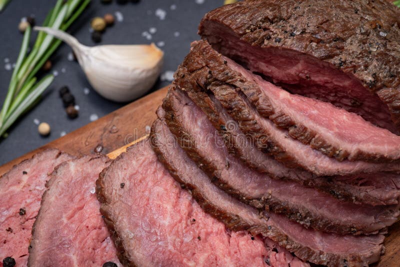 Geschnittenes bäuerisches saftiges Mais-Roastbeef geschmückt mit Tomaten, frischen Rosemary Herb-, Knoblauch-und Regenbogen-Pfeff lizenzfreie stockfotos Geschnittenes bäuerisches saftiges Mais-Roastbeef geschmückt mit Tomaten, frischen Rosemary Herb-, Knoblauch-und Regenbogen-Pfeff lizenzfreie stockfotos