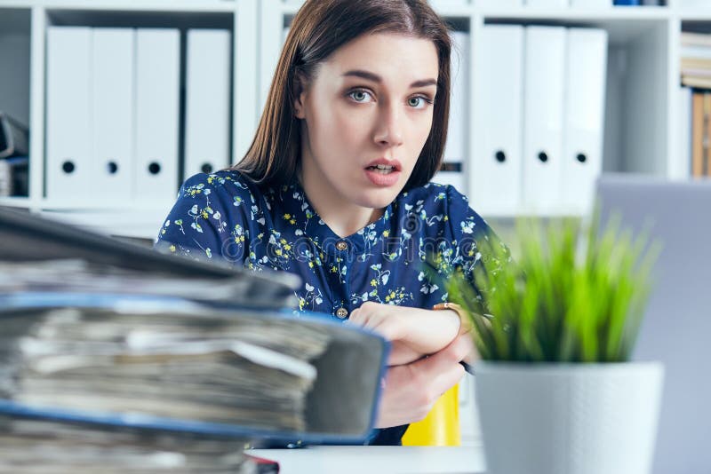 Geschokte vrouwelijke manager die haar horloge dichtbij een stapel van documenten bekijken Uiterste termijnconcept stock foto Geschokte vrouwelijke manager die haar horloge dichtbij een stapel van documenten bekijken Uiterste termijnconcept stock foto