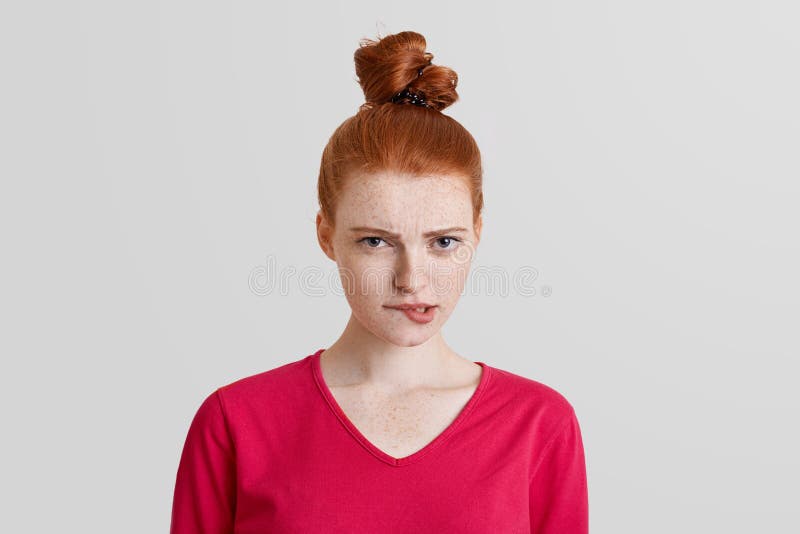 Geschossen von der disconetent redhaired Frau mit Haarknoten, ist Kurven und Bisslippen, Blicke mit unglücklichem Ausdruck direkt lizenzfreies stockbild Geschossen von der disconetent redhaired Frau mit Haarknoten, ist Kurven und Bisslippen, Blicke mit unglücklichem Ausdruck direkt lizenzfreies stockbild