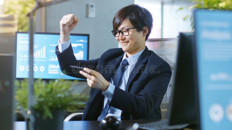 Geschoten van de Gelukkige Aziatische Zakenman Winning van het Oosten in Mobiel Spel royalty-vrije stock foto's Geschoten van de Gelukkige Aziatische Zakenman Winning van het Oosten in Mobiel Spel royalty-vrije stock foto's
