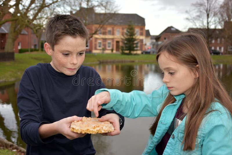 Geschwister, die Gebäck teilen lizenzfreie stockfotos Geschwister, die Gebäck teilen lizenzfreie stockfotos