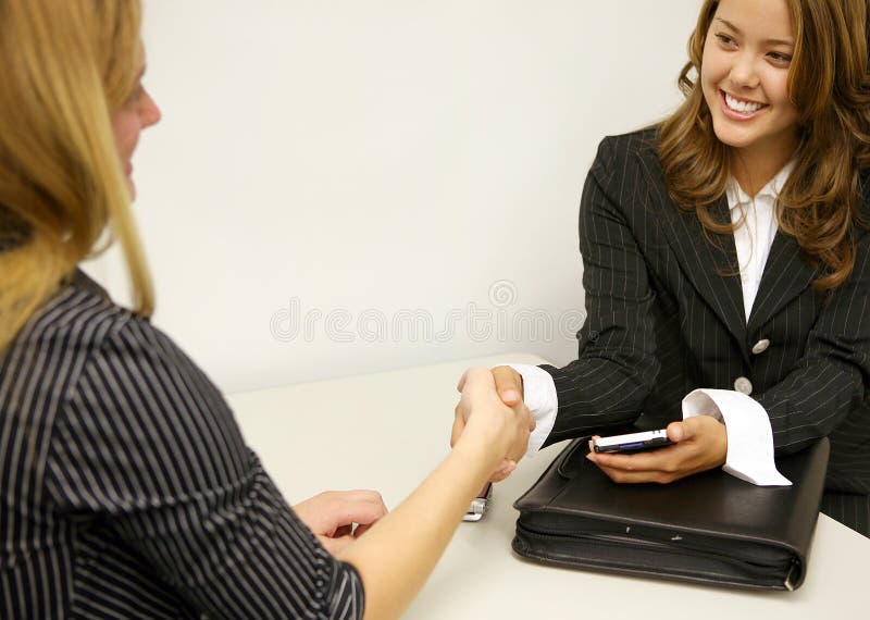 A business deal between two women concluding with a handshake. A business deal between two women concluding with a handshake