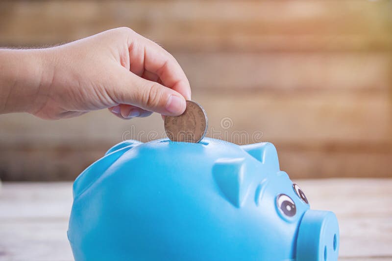 Geschäfts- oder Finanzeinsparungskonzept mit der Hand, die Münze in b setzt stockfotografie Geschäfts- oder Finanzeinsparungskonzept mit der Hand, die Münze in b setzt stockfotografie