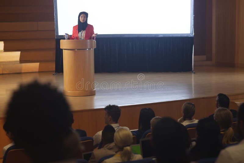 Geschäftsfrau, die Rede vor Publikum im Auditorium gibt stockfotografie Geschäftsfrau, die Rede vor Publikum im Auditorium gibt stockfotografie