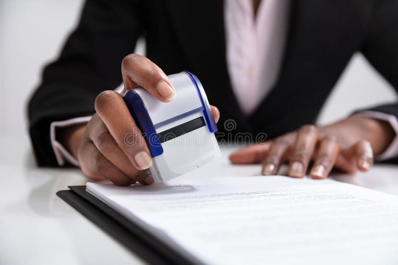 Close-up Of Businesswoman Putting Stamp On Documents In The Office. Close-up Of Businesswoman Putting Stamp On Documents In The Office