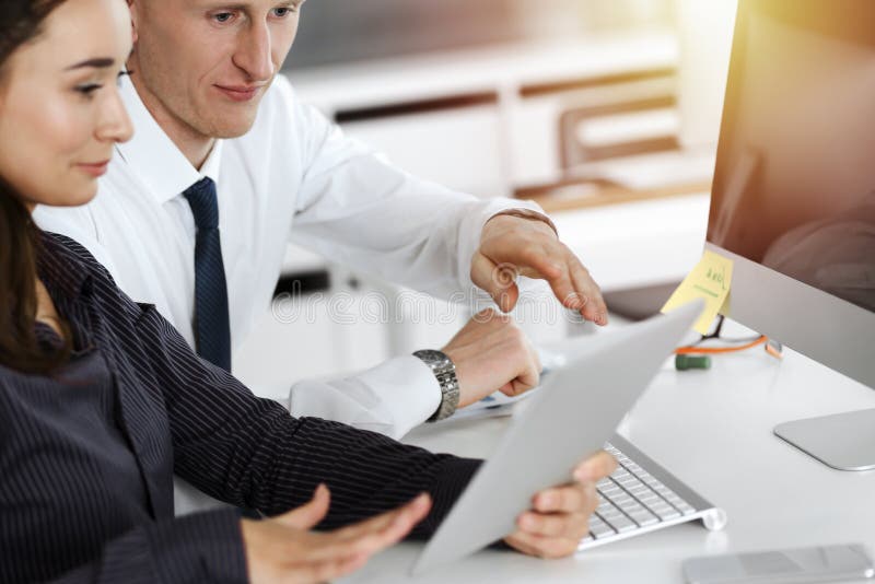 Geschäftsfrau und Mann diskutieren Fragen während der Verwendung von Computer am Arbeitsplatz in sonnigen Büro lizenzfreies stockfoto
