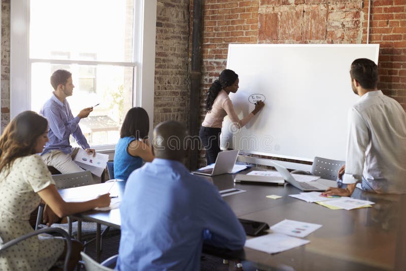 Geschäftsfrau-At Whiteboard In-Sitzung über Brainstorming stockfotos