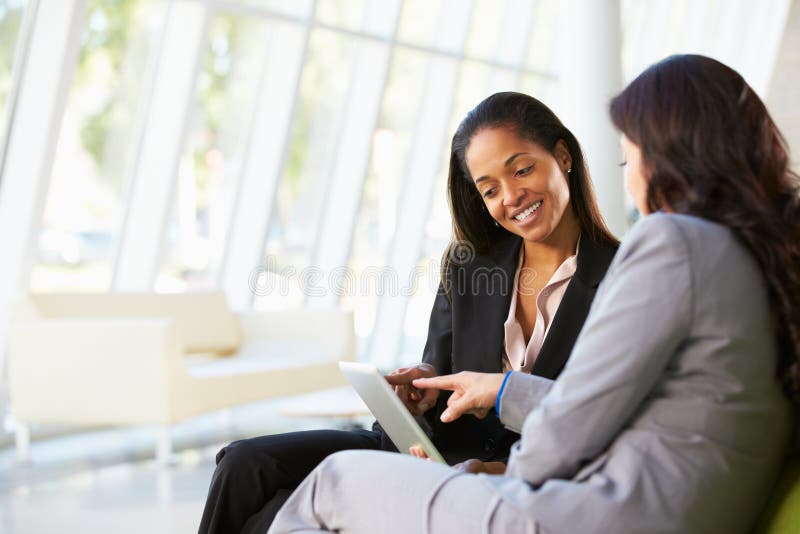 Geschäftsfrauen mit Digital-Tablette, die im modernen Büro sitzt lizenzfreies stockfoto Geschäftsfrauen mit Digital-Tablette, die im modernen Büro sitzt lizenzfreies stockfoto