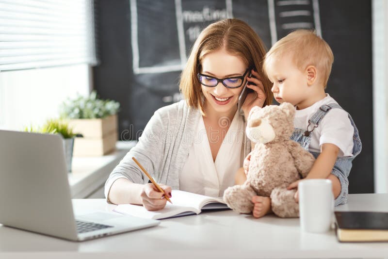 Geschäftsfraumutterfrau mit dem Kleinkind, das am Computer arbeitet stockfotografie