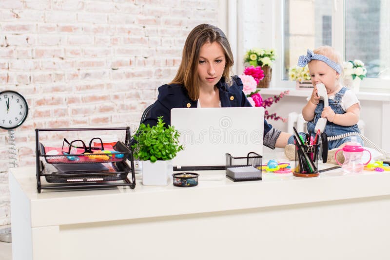 Geschäftsfraumutterfrau mit einer Tochter, die am Computer arbeitet lizenzfreie stockfotos