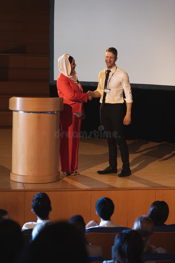 Geschäftskollegestellung und Diskussion mit einander vor dem Publikum im Auditorium lizenzfreie stockfotos Geschäftskollegestellung und Diskussion mit einander vor dem Publikum im Auditorium lizenzfreie stockfotos
