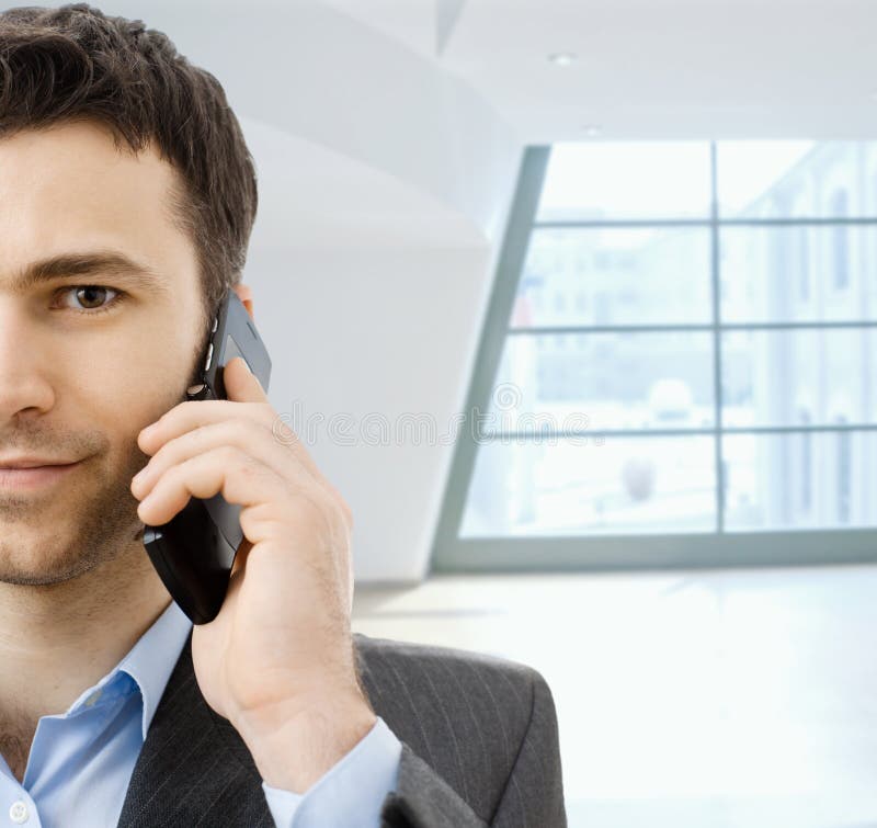 Closeup portrait of casual businessman talking on mobile phone, standing in office lobby. Closeup portrait of casual businessman talking on mobile phone, standing in office lobby.