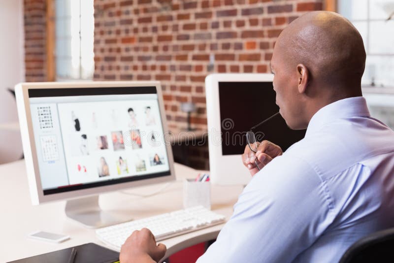 Geschäftsmann, der Computermonitor im Büro betrachtet stockfotografie Geschäftsmann, der Computermonitor im Büro betrachtet stockfotografie