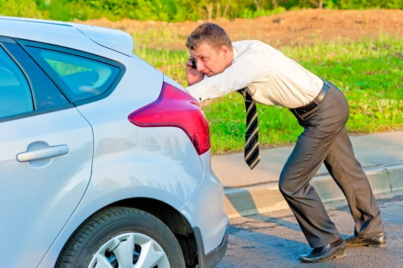 Geschäftsmann, der ein Auto drückt und am Telefon spricht stockfoto Geschäftsmann, der ein Auto drückt und am Telefon spricht stockfoto