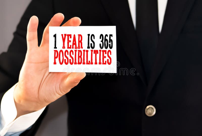 Business man holding a red notebook and white card with text 1 Year 365 Possibilities. Financial concept. Business man holding a red notebook and white card with text 1 Year 365 Possibilities. Financial concept