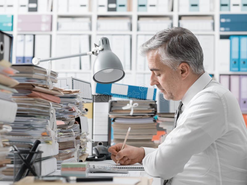 Geschäftsmann, der im Büro und in den Stapel der Schreibarbeit arbeitet lizenzfreie stockfotos