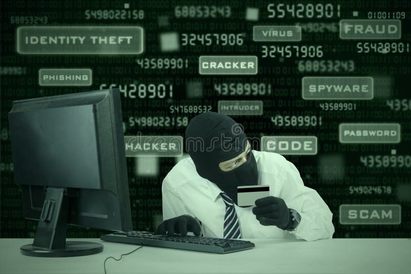 Internet Theft - businessman wearing a mask and holding a credit card while sat behind a computer. Internet Theft - businessman wearing a mask and holding a credit card while sat behind a computer