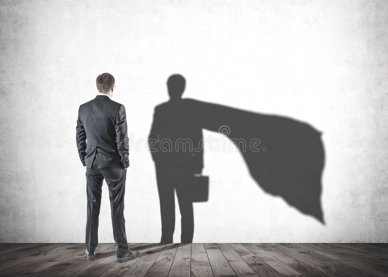 Geschäftsmann, der seinen Supermannschatten betrachtet stockfoto