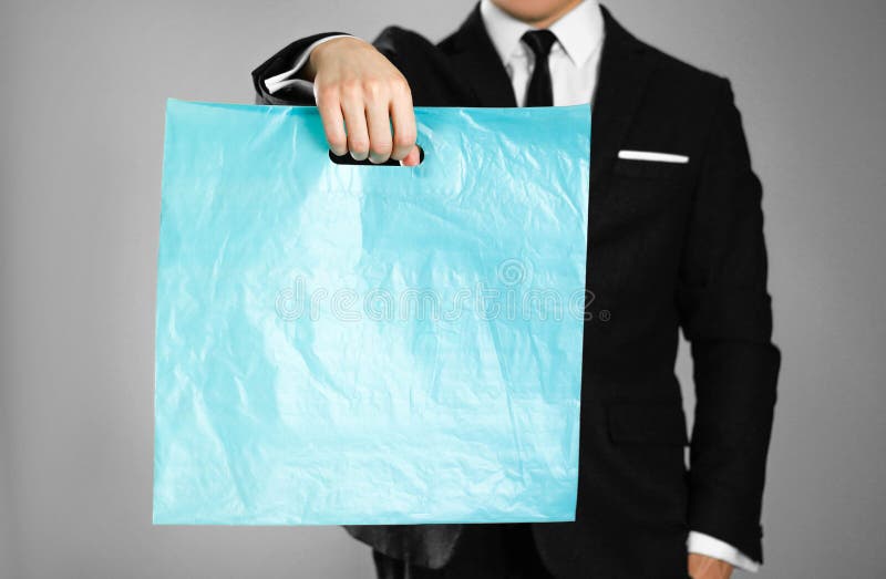 Geschäftsmann in einem schwarzen Anzug, der eine blaue Plastiktasche hält Abschluss oben Lokalisierter Hintergrund stockbilder Geschäftsmann in einem schwarzen Anzug, der eine blaue Plastiktasche hält Abschluss oben Lokalisierter Hintergrund stockbilder