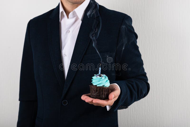 Businessman holding birthday cupcake with birning candle. Business greeting card. 1 year. Corporate party. Copy space for text. Businessman holding birthday cupcake with birning candle. Business greeting card. 1 year. Corporate party. Copy space for text