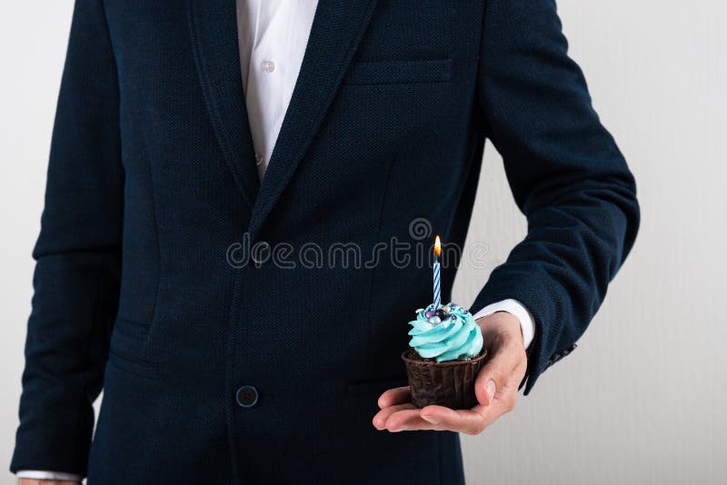 Businessman holding birthday cupcake with birning candle. Business greeting card. 1 year. Corporate party. Copy space for text. Businessman holding birthday cupcake with birning candle. Business greeting card. 1 year. Corporate party. Copy space for text