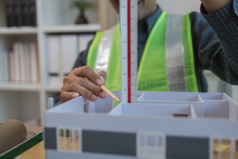 Geschäftsmann oder Architekt mit Modell eines Hauses, der in Büroarchitekten arbeitet und mit Planen Ingenieur inspect arbeitet stockfotografie
