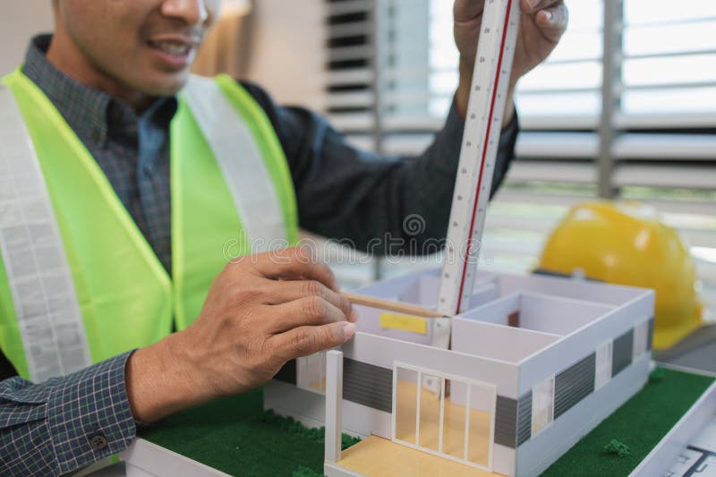 Geschäftsmann oder Architekt mit Modell eines Hauses, der in Büroarchitekten arbeitet und mit Planen Ingenieur inspect arbeitet stockfoto