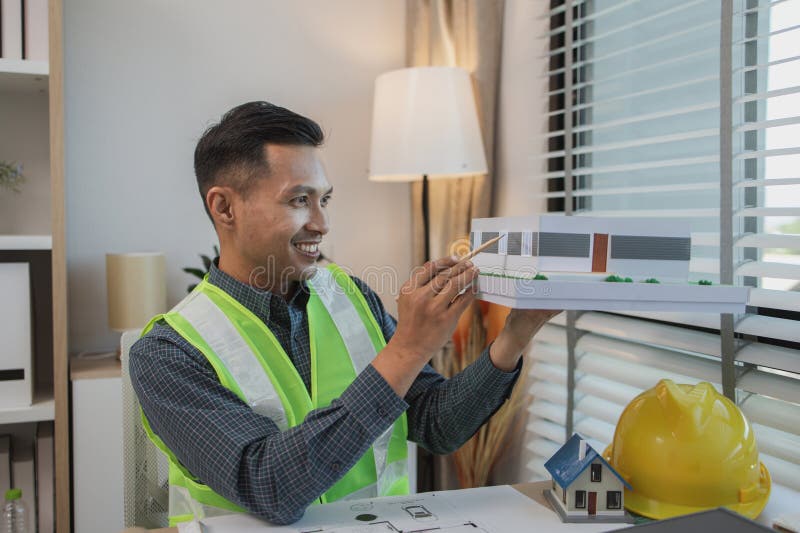 Geschäftsmann oder Architekt mit Modell eines Hauses, der in Büroarchitekten arbeitet und mit Planen Ingenieur inspect arbeitet lizenzfreies stockfoto