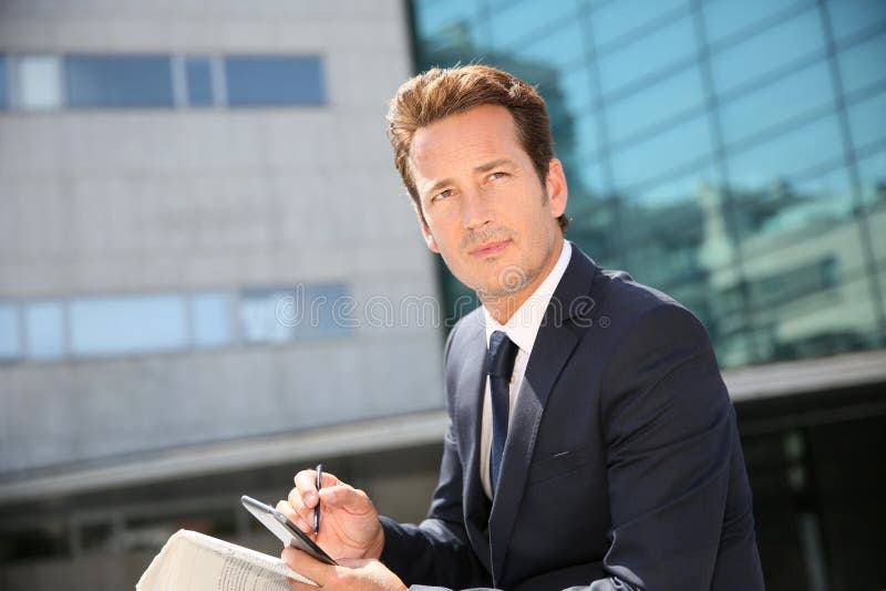 Geschäftsmann Sitting In Front Of Office Building lizenzfreies stockfoto Geschäftsmann Sitting In Front Of Office Building lizenzfreies stockfoto