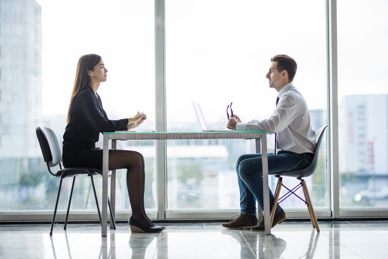 Geschäftsmann und Frau, die eine Diskussion im Büro vertraulich bei Tisch gegen Fenster hat lizenzfreies stockfoto Geschäftsmann und Frau, die eine Diskussion im Büro vertraulich bei Tisch gegen Fenster hat lizenzfreies stockfoto