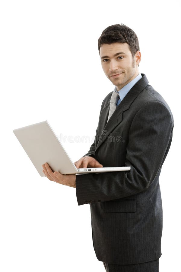 Businessman using laptop computer, standing and holding the machine in hand, smiling. Isolated on white background. Businessman using laptop computer, standing and holding the machine in hand, smiling. Isolated on white background.