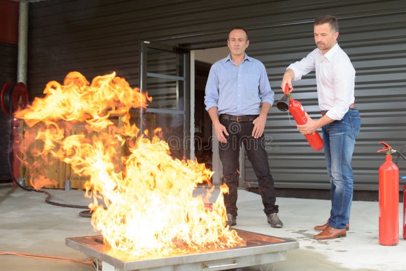 Geschäftsmann unter Verwendung des Feuerlöschers während des Feuertrainings lizenzfreies stockbild Geschäftsmann unter Verwendung des Feuerlöschers während des Feuertrainings lizenzfreies stockbild