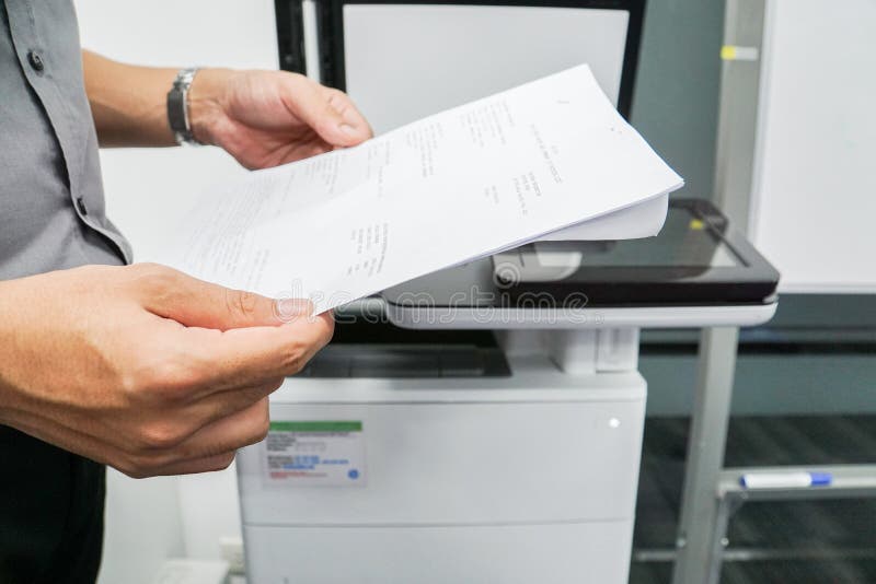 Close up businessman hold paper for scanning on the office printer. Close up businessman hold paper for scanning on the office printer