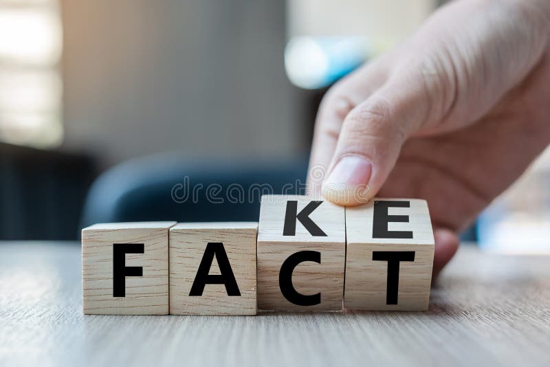 Business man hand holding wooden cube with flip over block FAKE to FACT word on table background. News, solution and business concepts. Business man hand holding wooden cube with flip over block FAKE to FACT word on table background. News, solution and business concepts