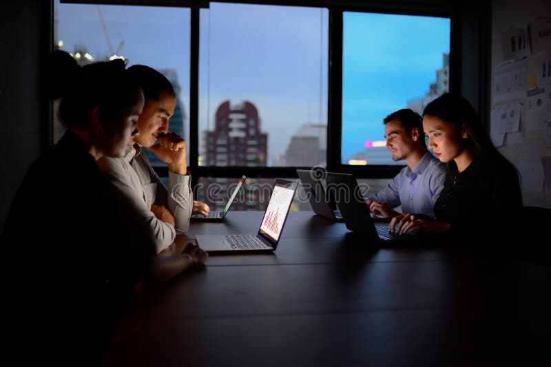 Geschäftsteam, das über die Zeit hinaus mit Computer nachts arbeitet lizenzfreies stockbild Geschäftsteam, das über die Zeit hinaus mit Computer nachts arbeitet lizenzfreies stockbild