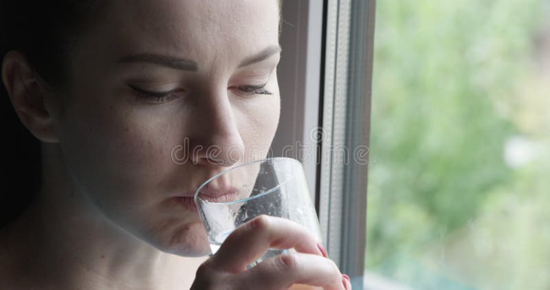 Gesicht der Frau eine Tablette nehmen und ein Glas Wasser Alkohol das Fenster bereitstehend