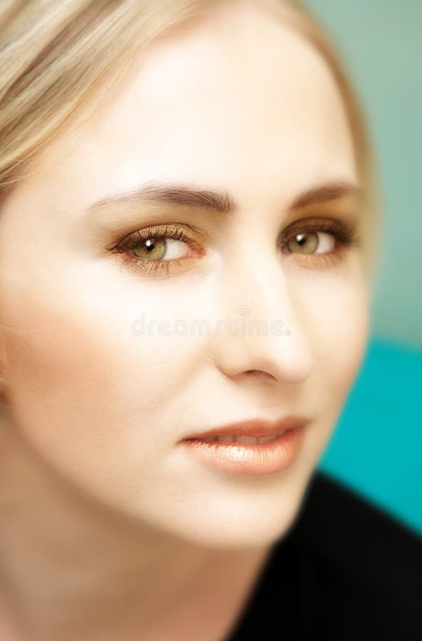 Woman with short hair and green eyes against soft green background. Woman with short hair and green eyes against soft green background