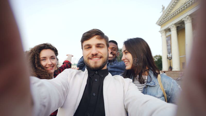 Gesichtspunkt schoss von der gemischtrassigen Gruppe Touristen, die selfie im Stadtzentrum nehmen, das Kamera hält und zusammen m