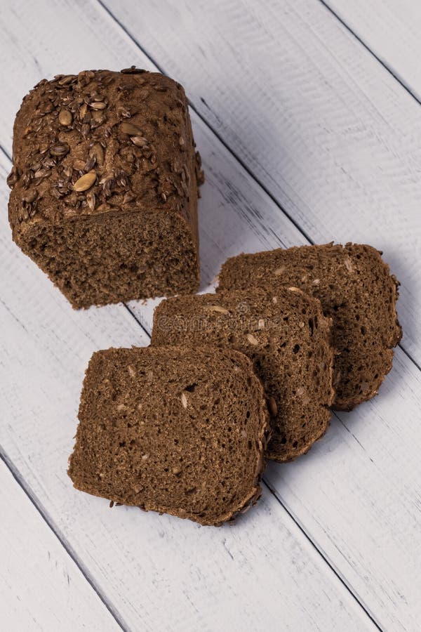 Gesloten roggebrood met zaden op een witte houten achtergrond Het brood van donker brood royalty-vrije stock foto Gesloten roggebrood met zaden op een witte houten achtergrond Het brood van donker brood royalty-vrije stock foto