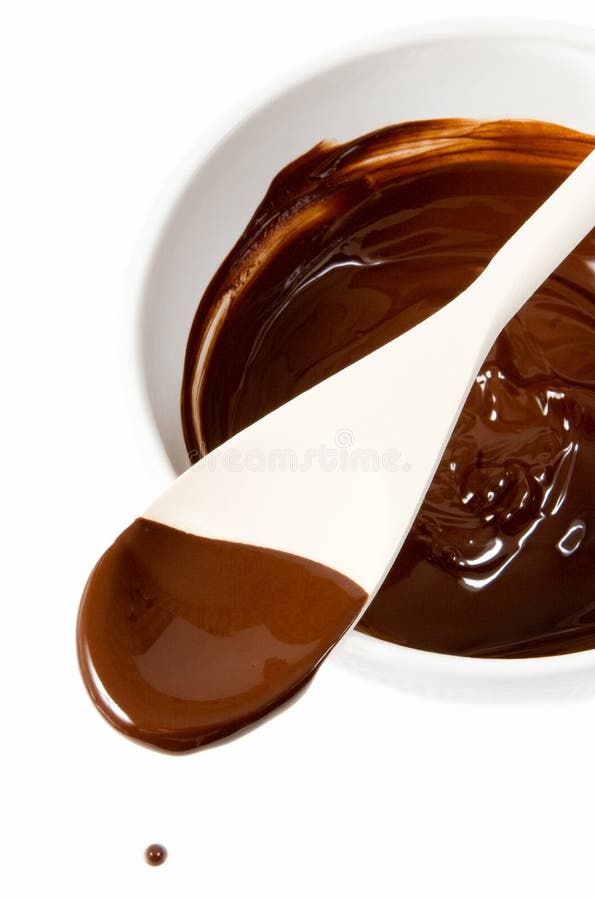 Melted dark chocolate dripping from the wooden spoon. Melted dark chocolate dripping from the wooden spoon