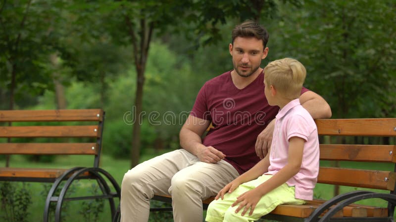 Gesprek tussen vader en zoon in park, houdende van papa die adviezen geven aan jong geitje