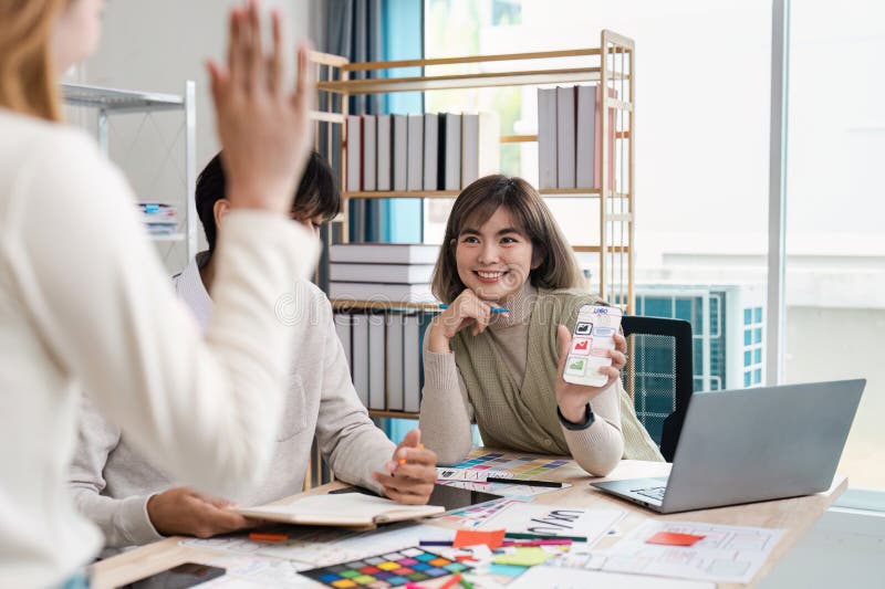 Gestaltung und Teamdynamik. Eine lächelnde Designerin präsentiert ihre Arbeit während einer Brainstorming-Sitzung der UX-Benutzero stockbilder
