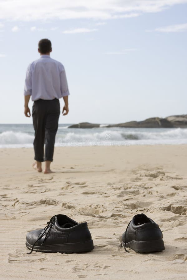 Gestionnaire marchant nu-pieds sur la plage image libre de droits Gestionnaire marchant nu-pieds sur la plage image libre de droits