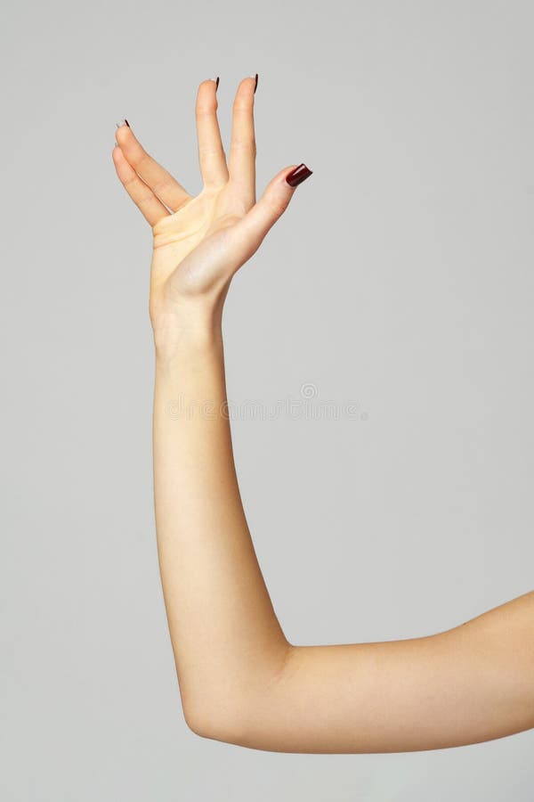 Gesto di mano della giovane donna sullo sfondo grigio immagine stock