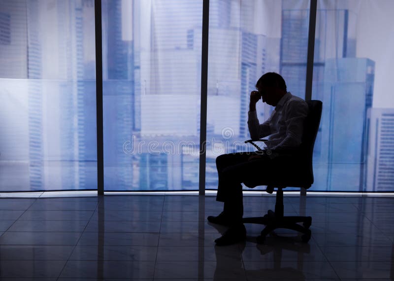 Gestraffter Geschäftsmann Sitting On Chair durch Büro-Fenster stockbilder Gestraffter Geschäftsmann Sitting On Chair durch Büro-Fenster stockbilder