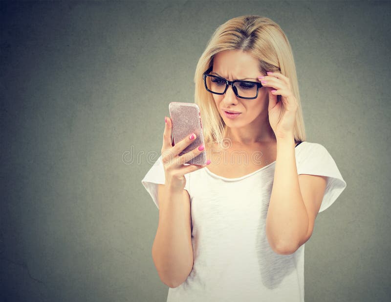 Gestörte umgekippte Frau in den Gläsern, die ihren Handy mit Frustration betrachten