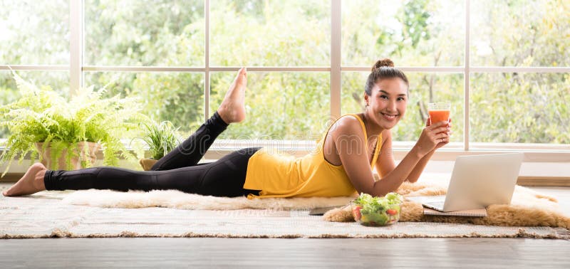 Gesunde Asiatin, die auf dem Boden isst den Salat schaut entspannt und bequem liegt stockfotografie Gesunde Asiatin, die auf dem Boden isst den Salat schaut entspannt und bequem liegt stockfotografie