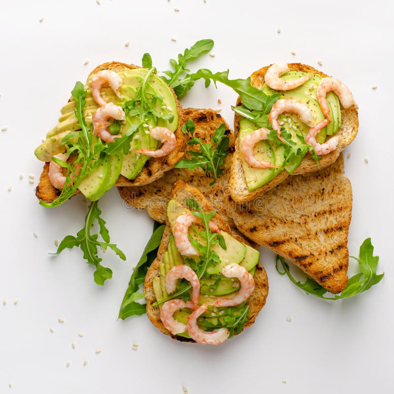 Gesunde leckere Snacks Toasts mit Avocado, Garnelen und Arugula auf weißem Hintergrund lizenzfreies stockbild Gesunde leckere Snacks Toasts mit Avocado, Garnelen und Arugula auf weißem Hintergrund lizenzfreies stockbild