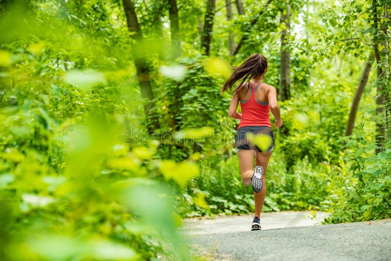 Gesunder aktiver Lebensstilfrauenläufer, der im Waldweg-Sportathletentraining im Freien in der grünen Natur rüttelt Sitzpersonenf