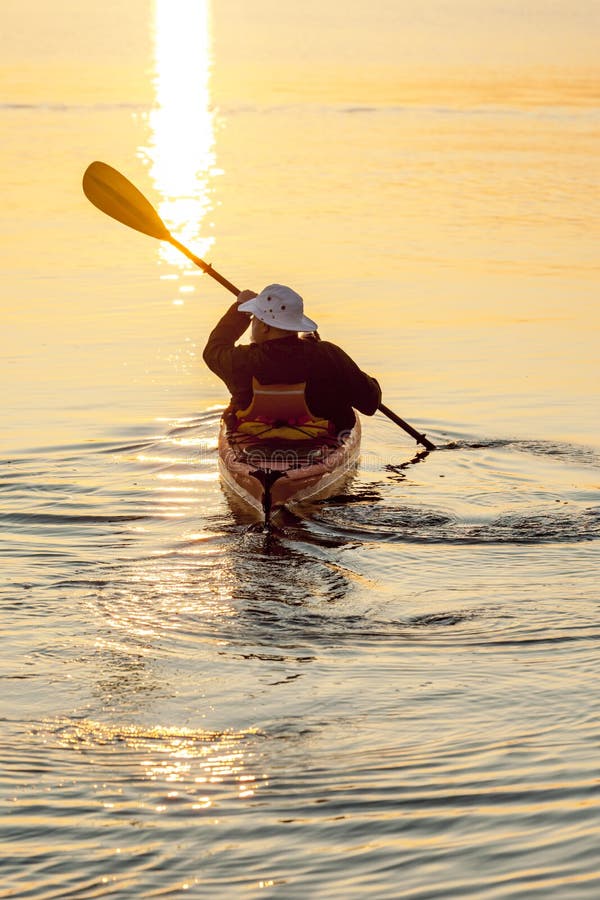 Gesunder, aktiver Seekajaken des älteren Mannes bei Sonnenaufgang oder Sonnenuntergang Abenteuerwassersportgenießen im Freien sic